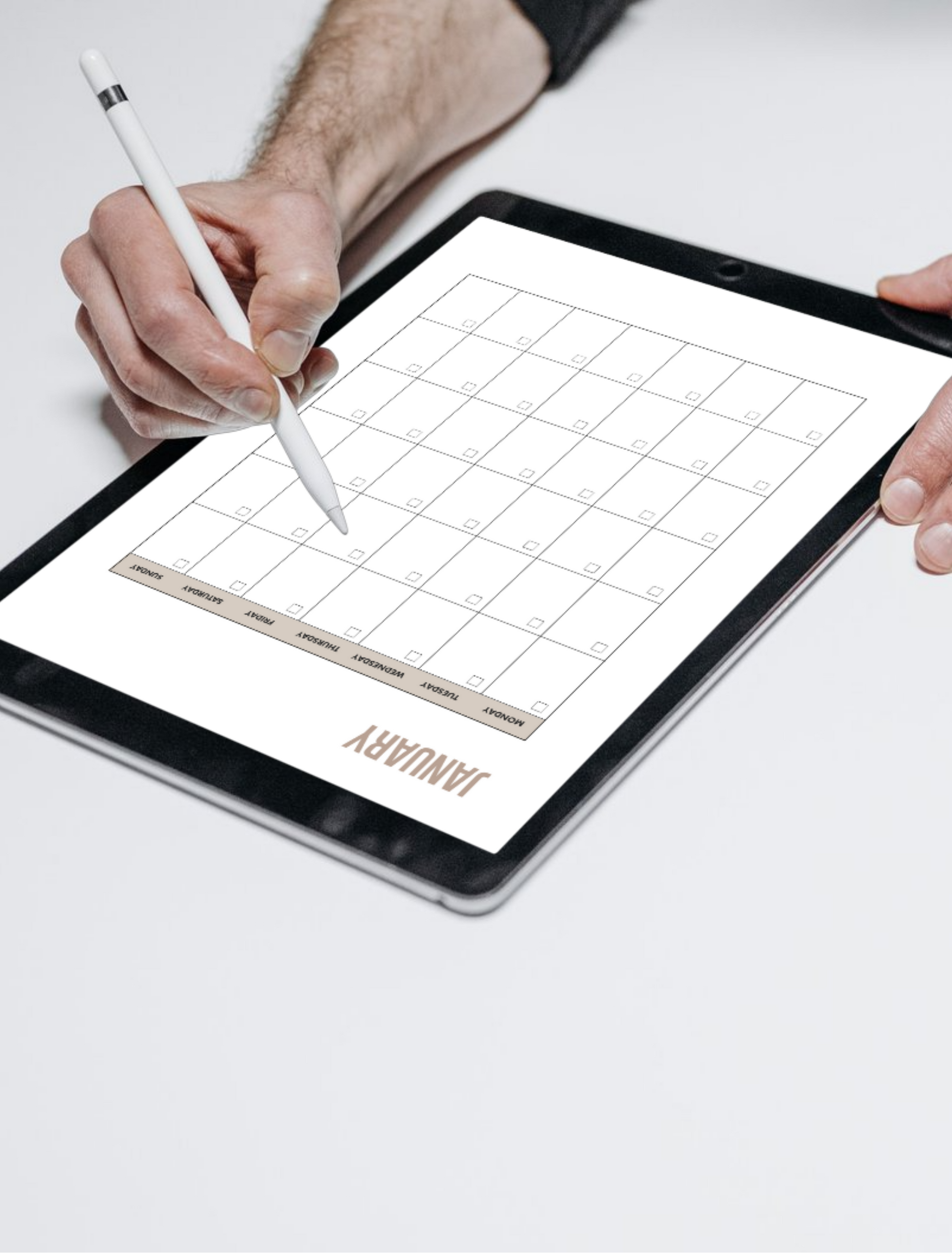 Person using a stylus on a digital tablet with a grid layout on a white surface